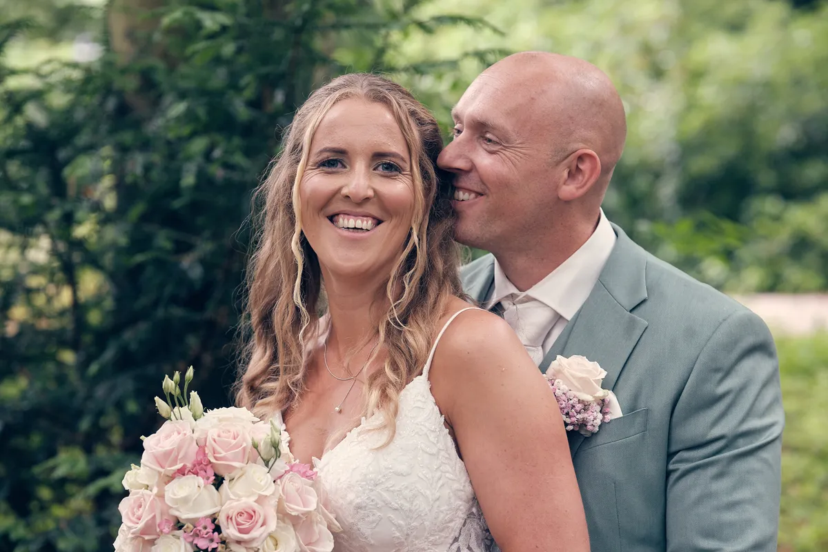Kim lacht met het boeket, Dennis met zijn arm om haar heen