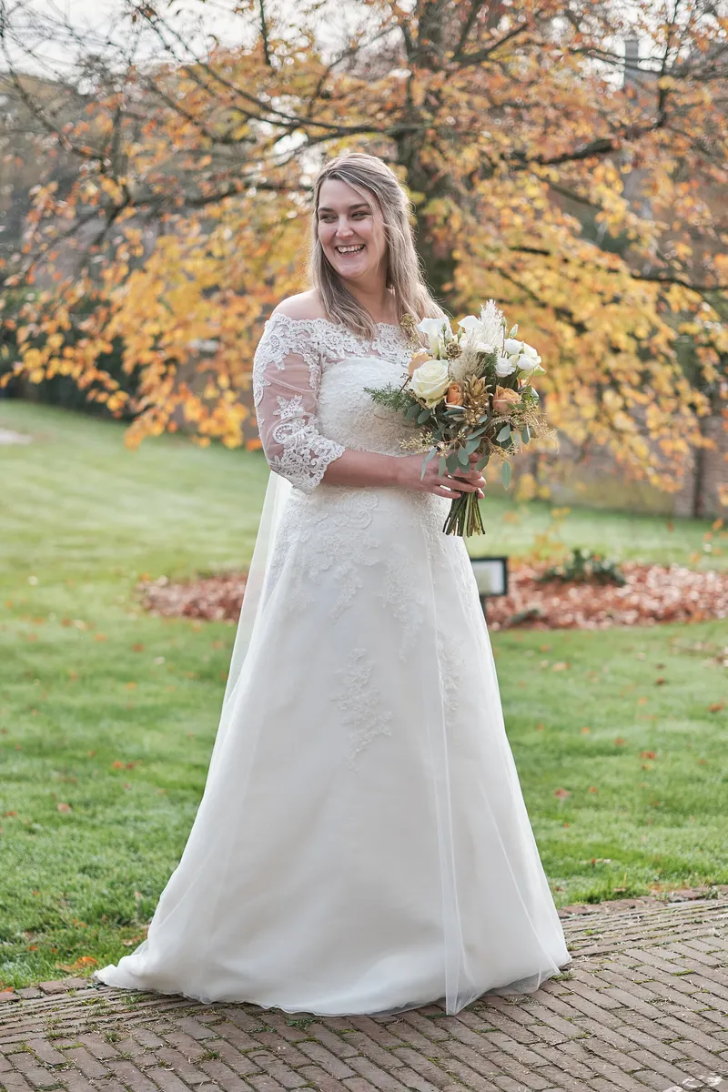 Wendy met haar boeket onder een boom met herfstbladeren