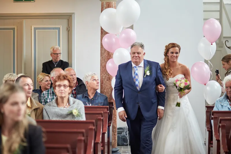 Trudy komt binnen aan de arm van haar vader