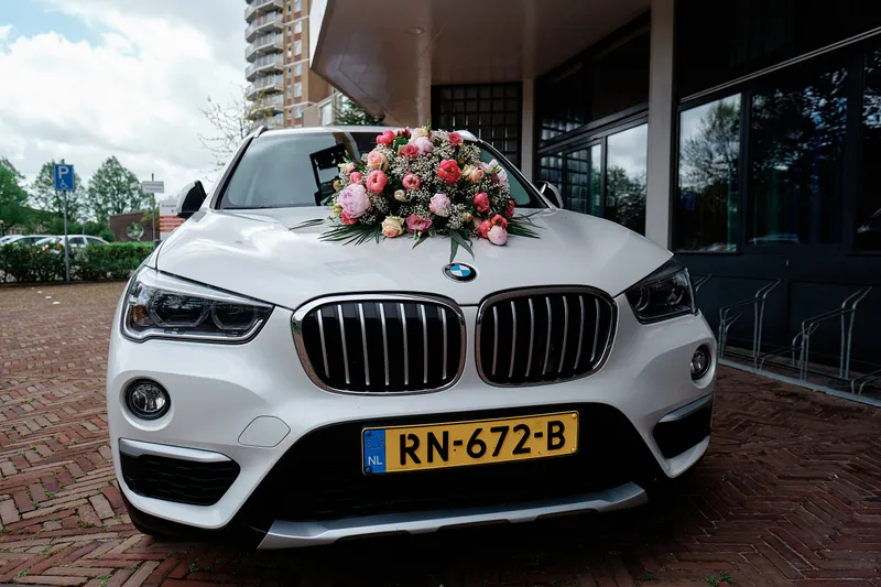 De witte trouwauto met bloemen op de motorkap