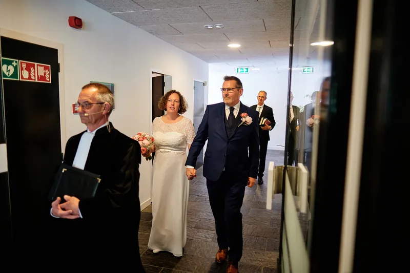 De voorganger loopt voor Jakob en Janneke uit door de gang