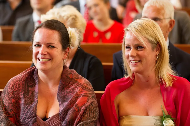 Twee gasten lachen in de kerkbank