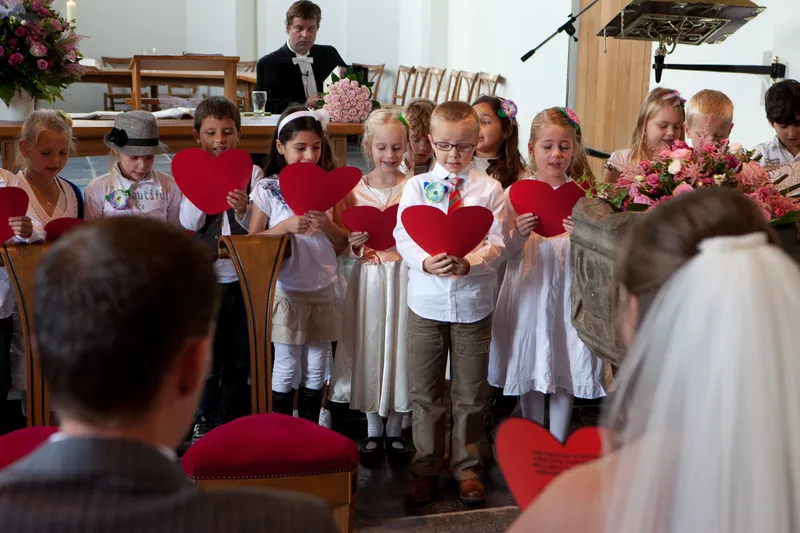De kinderen staan voorin de kerk met rode harten in hun handen