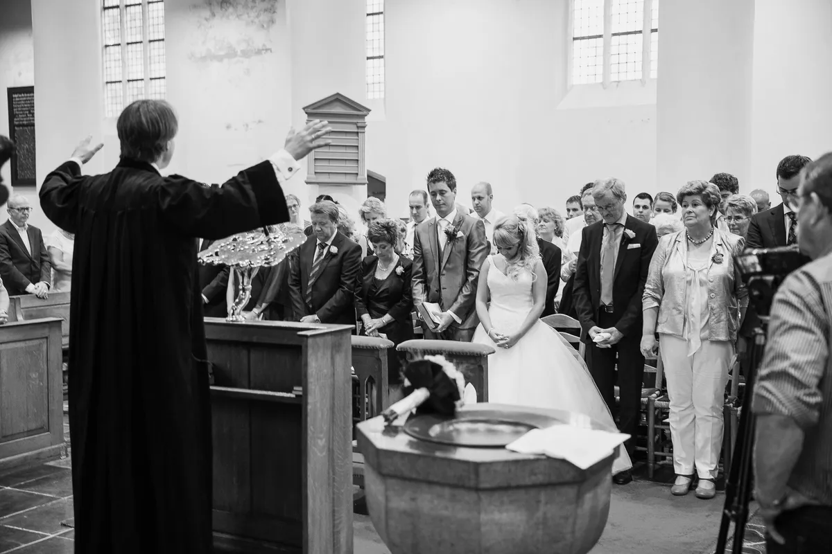 De dominee zegent het bruidspaar voor de hele kerk
