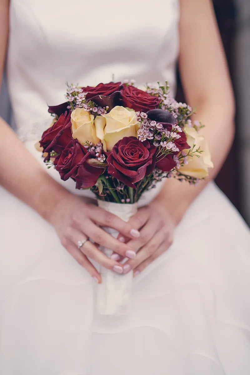 Het boeket met rode rozen in de handen van Caitriona
