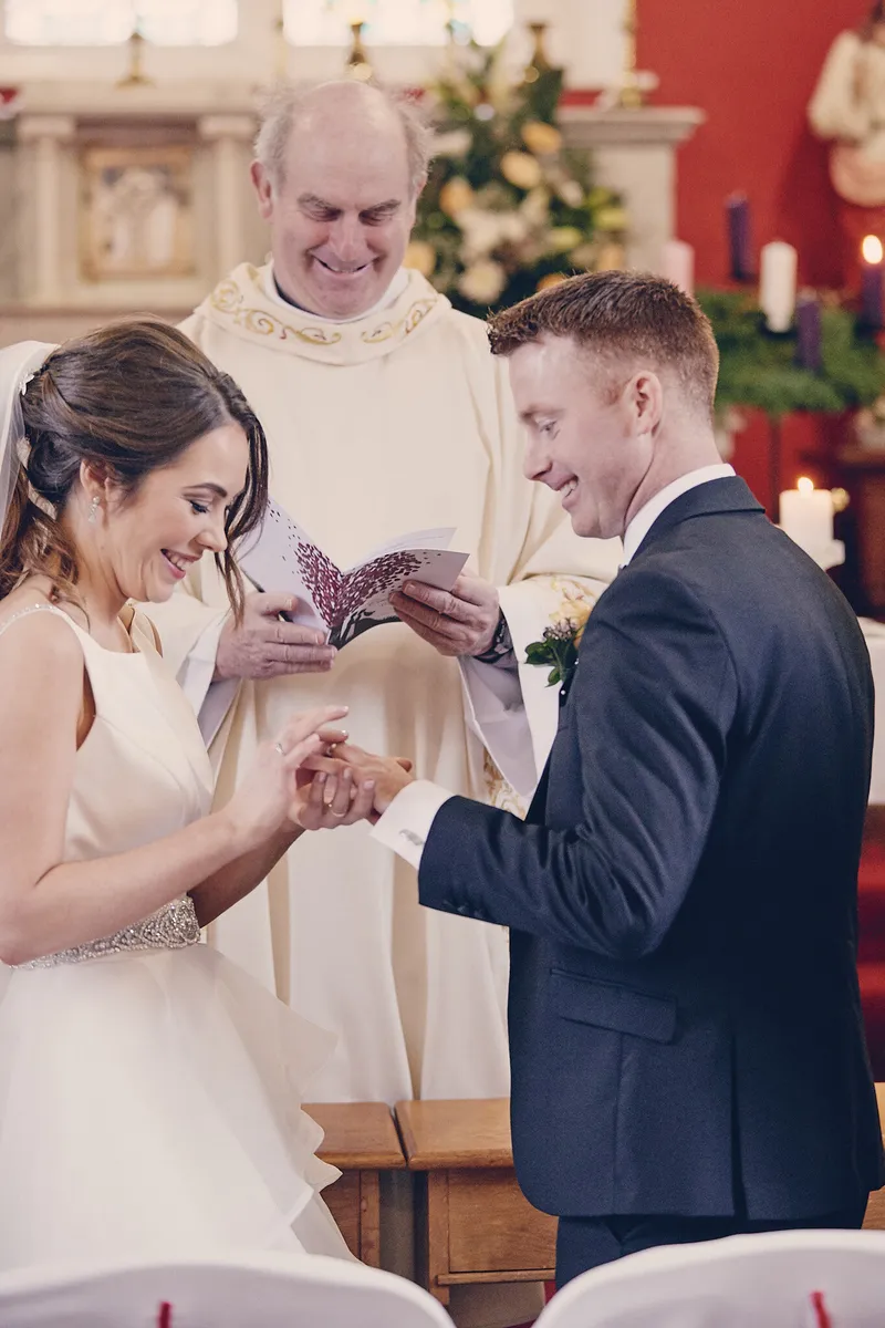 Caitriona en Shane bij de priester, met het boekje in hun handen