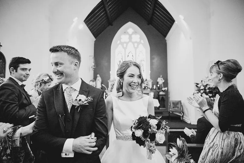 Shane en Caitriona lopen lachend de kerk uit, in zwart-wit