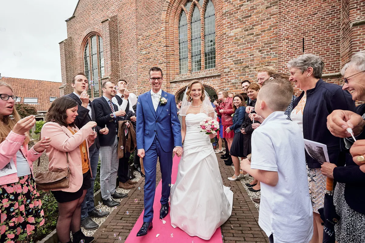Femke en Arjan lopen de kerk uit tussen de gasten