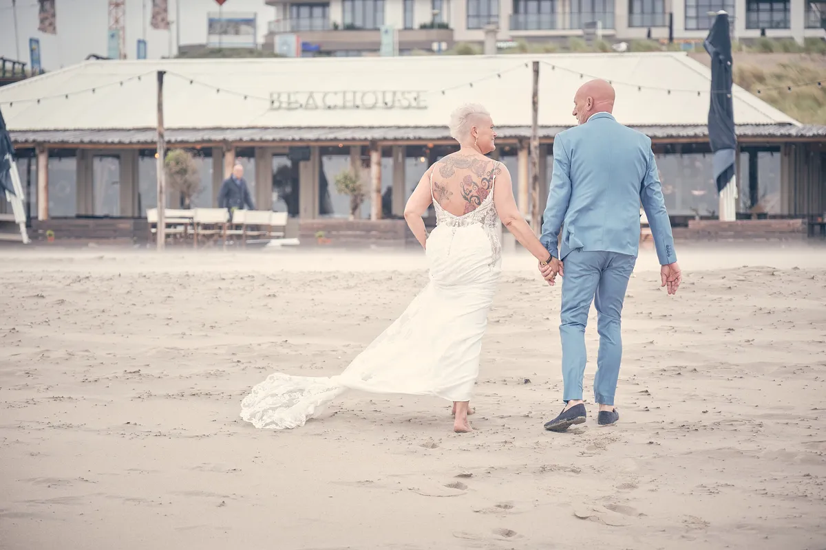 Silvia en Patrick lopen naar Beachhouse, haar jurk waait op
