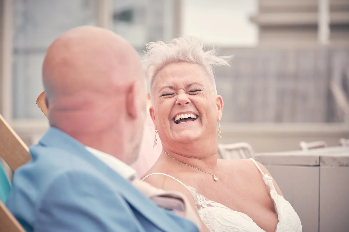 Silvia lacht in de strandstoel naast Patrick