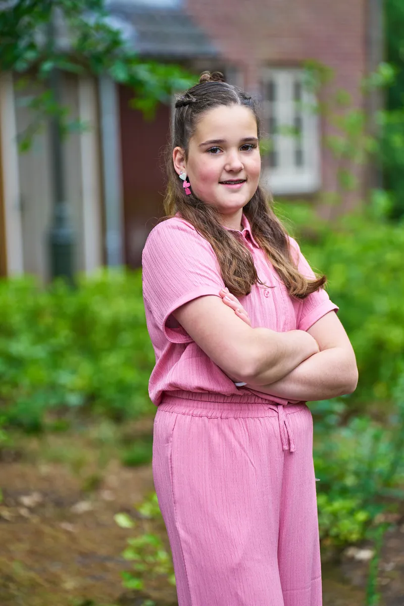 Hun dochter in een roze jumpsuit, met de armen over elkaar