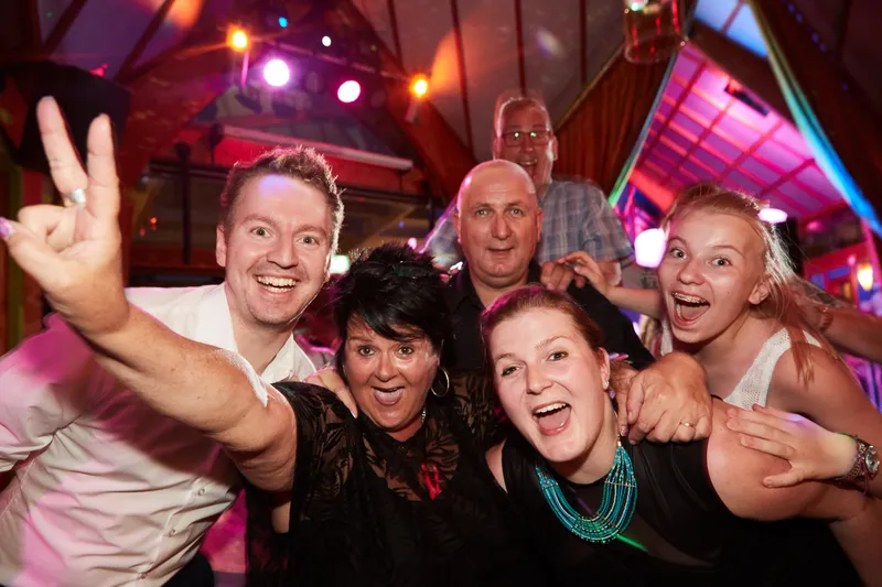 Gasten juichen met een peace-teken op de dansvloer