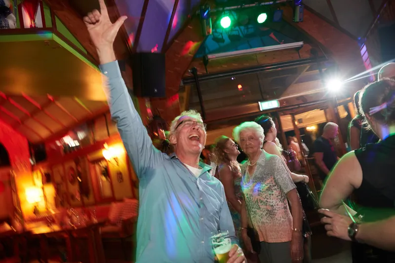 Een gast steekt zijn arm omhoog onder de discolampen