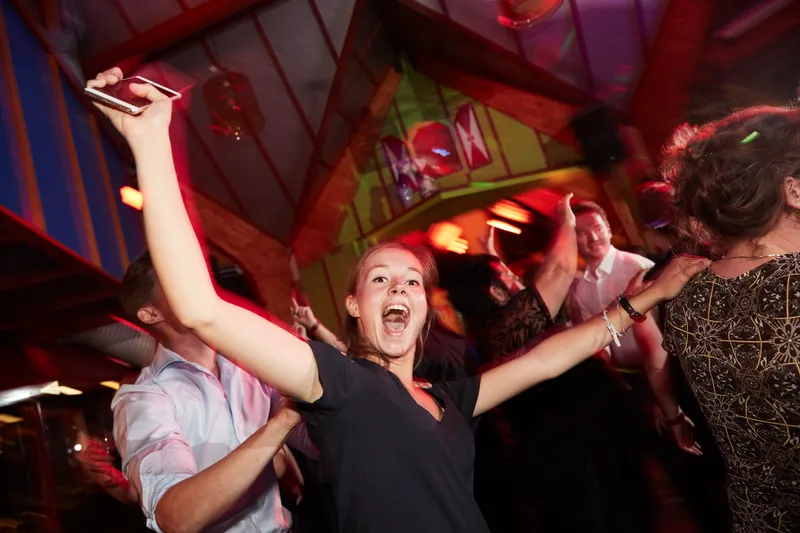 Een gast danst met de armen wijd onder het rode licht
