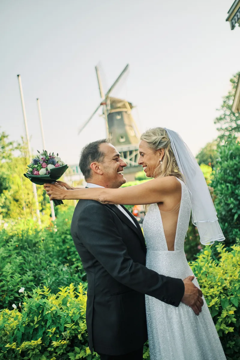 Wilfried en Liad omhelzen elkaar, met een molen op de achtergrond