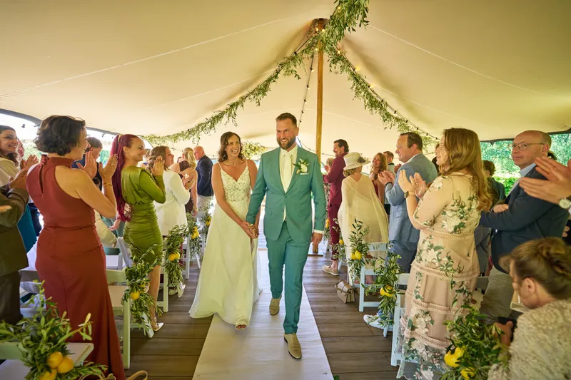 Michelle en Barrie lopen als getrouwd stel de tent uit, tussen de klappende gasten