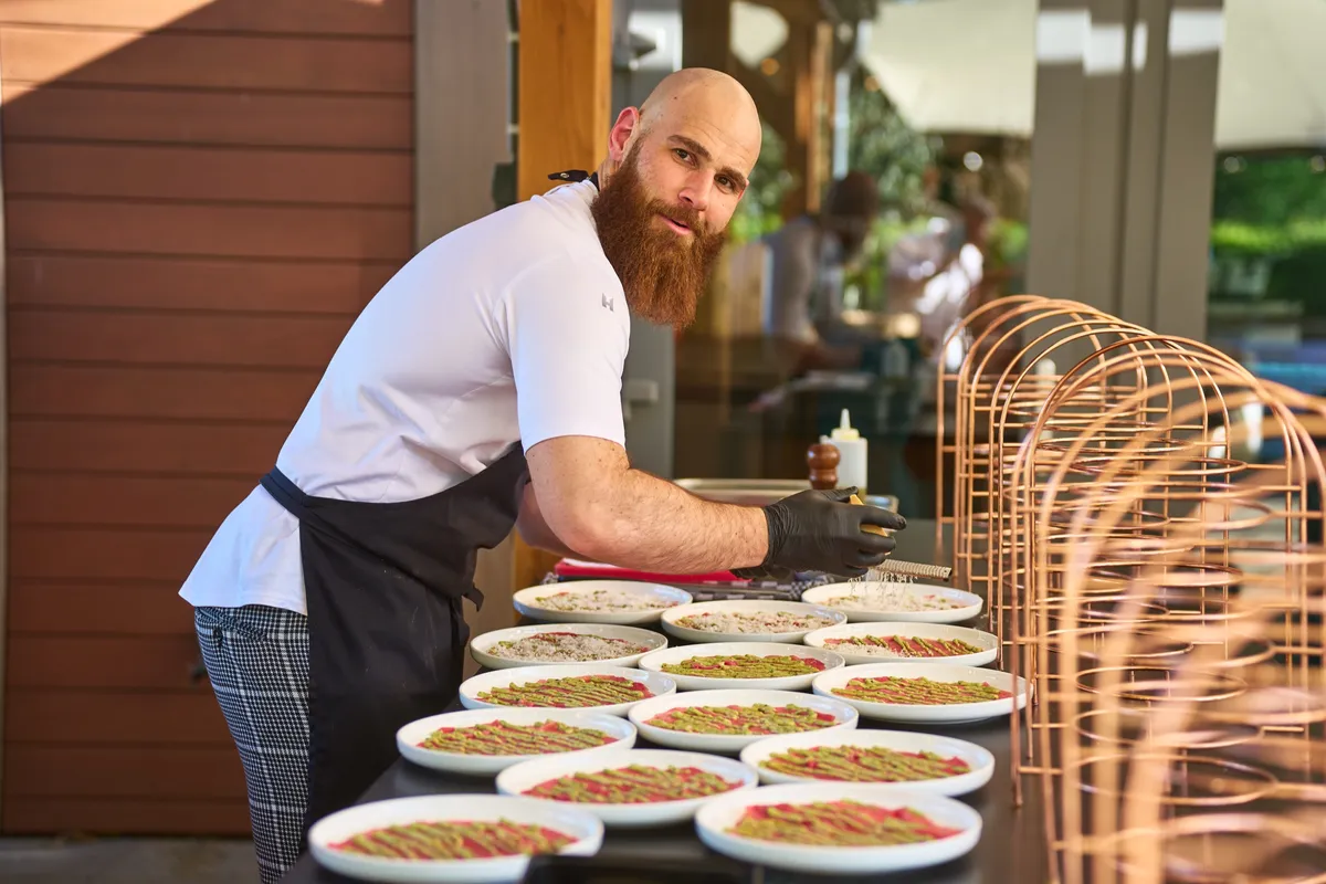 Een kok legt de voorgerechten op borden onder de overkapping