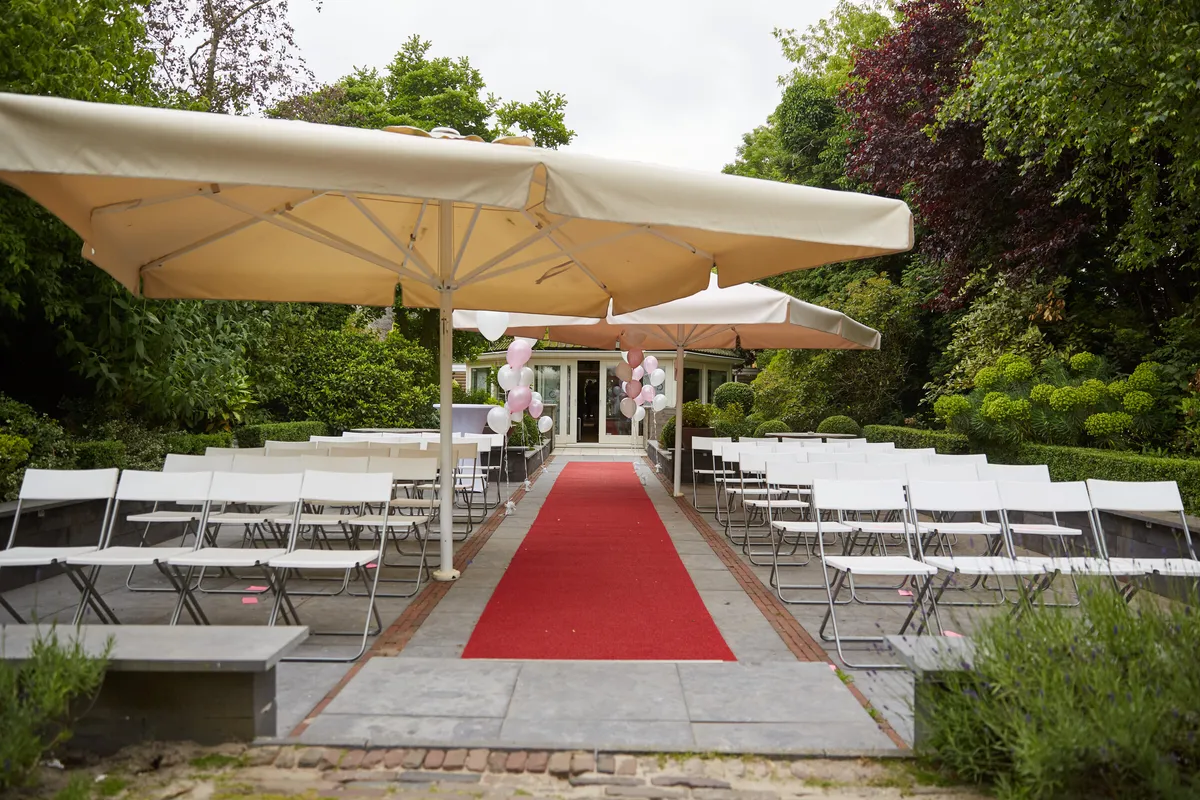 De ceremonieplek onder de parasols met de rode loper en witte stoelen