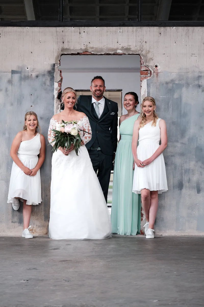 Marleen en Eric met de bruidsmeisjes voor een verweerde blauwe muur