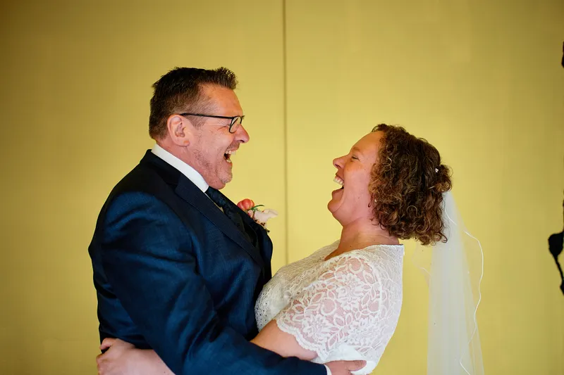Jakob en Janneke lachen voor een gele muur