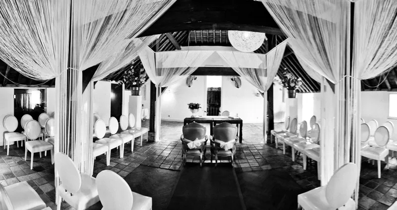 De trouwzaal met witte doeken onder het rieten dak, in zwart-wit