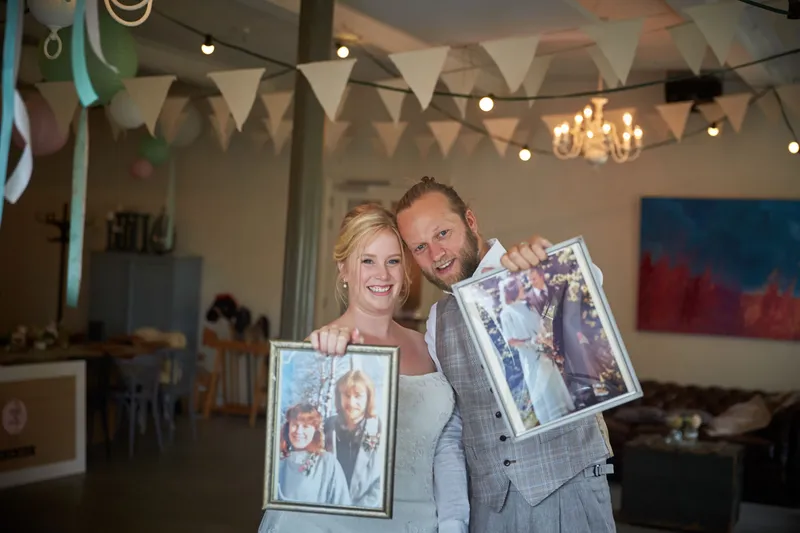 Akke en Rogier bekijken ingelijste foto’s tussen de vlaggetjes