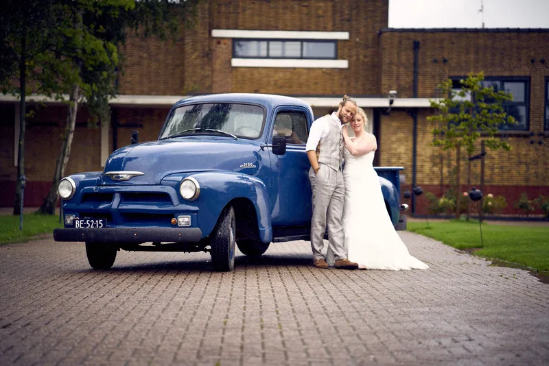 Akke en Rogier bij een blauwe oldtimer-pick-up voor het oude slachthuis