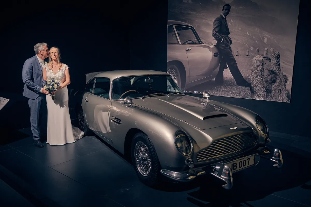 Ingeborg en Herre naast de zilveren Aston Martin in het Louwman Museum