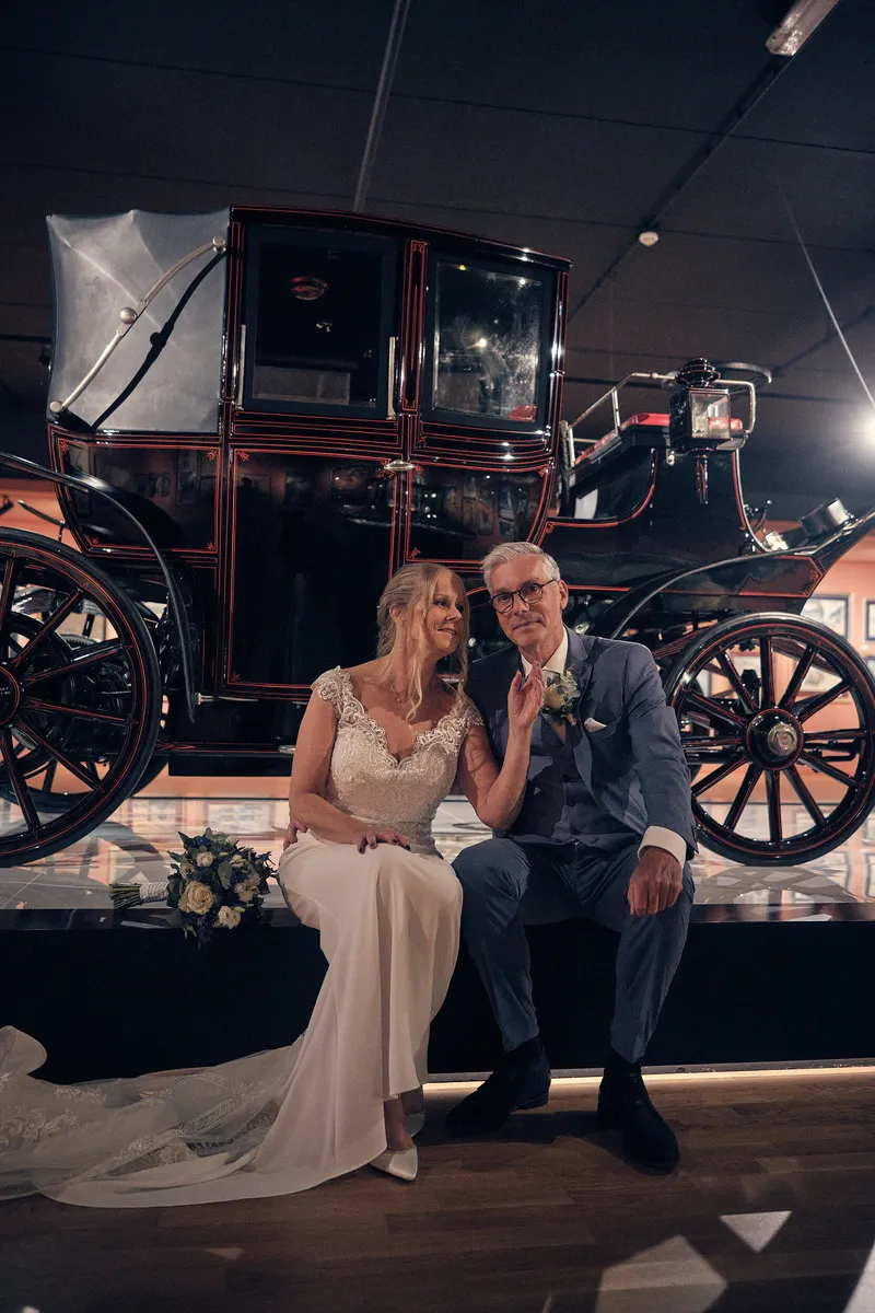 Ingeborg en Herre zitten op de treeplank van een oude auto