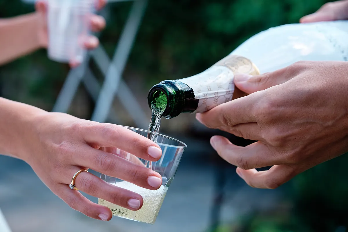 Champagne wordt ingeschonken, de trouwring glinstert aan de hand
