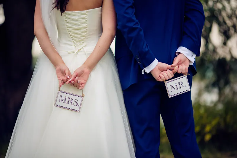 Mrs- en Mr-bordjes in hun handen achter de rug