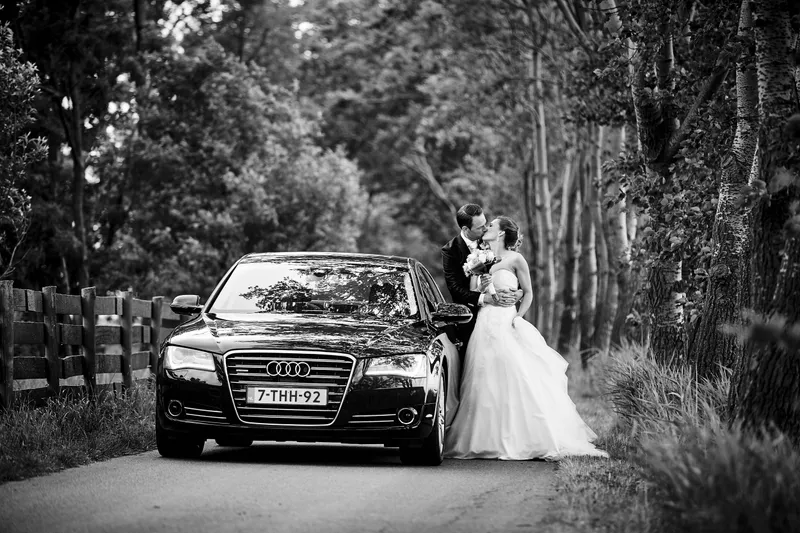 Trudy en Ron bij de zwarte Audi in een laan, in zwart-wit