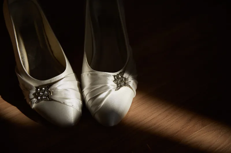 De witte bruidsschoenen in een streep zonlicht