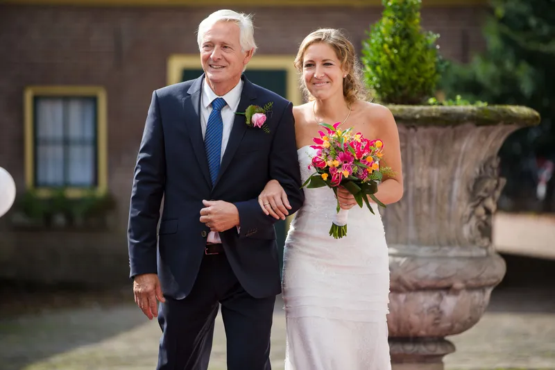 Karin loopt aan de arm van haar vader naar de ceremonie