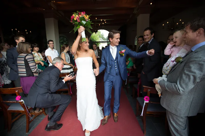 Karin steekt haar boeket in de lucht als ze de zaal verlaten