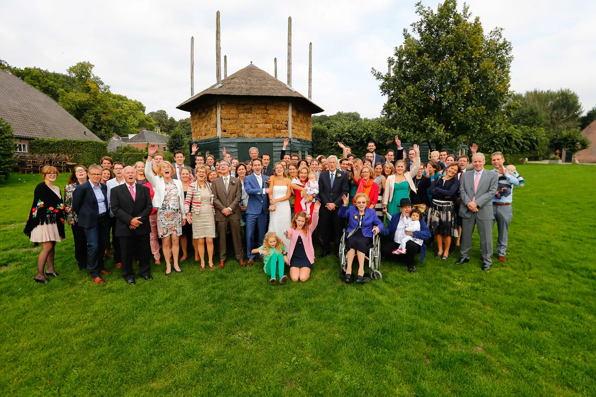 Groepsfoto met alle gasten op het grasveld, met de hooiberg erachter