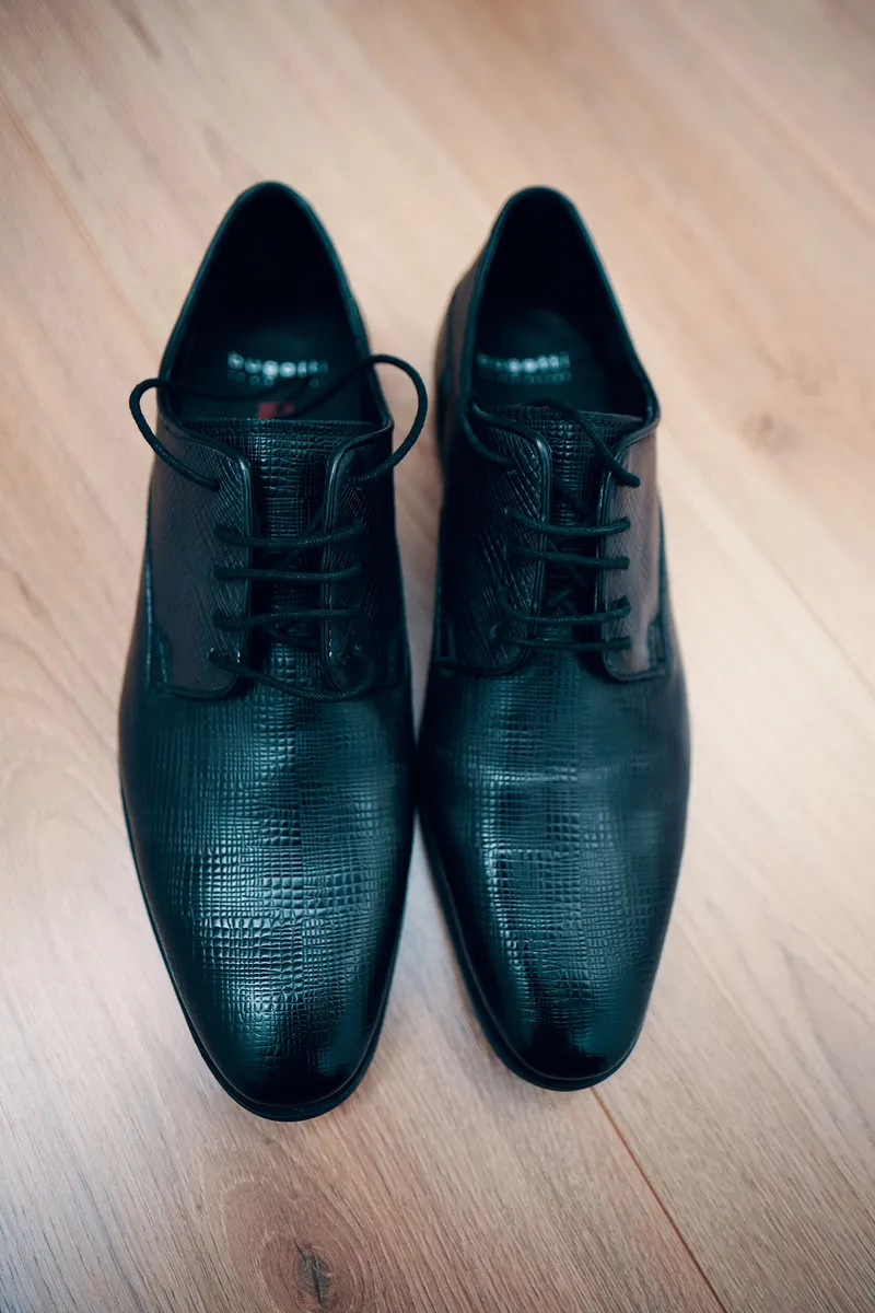 De zwarte schoenen van Maurice op de houten vloer