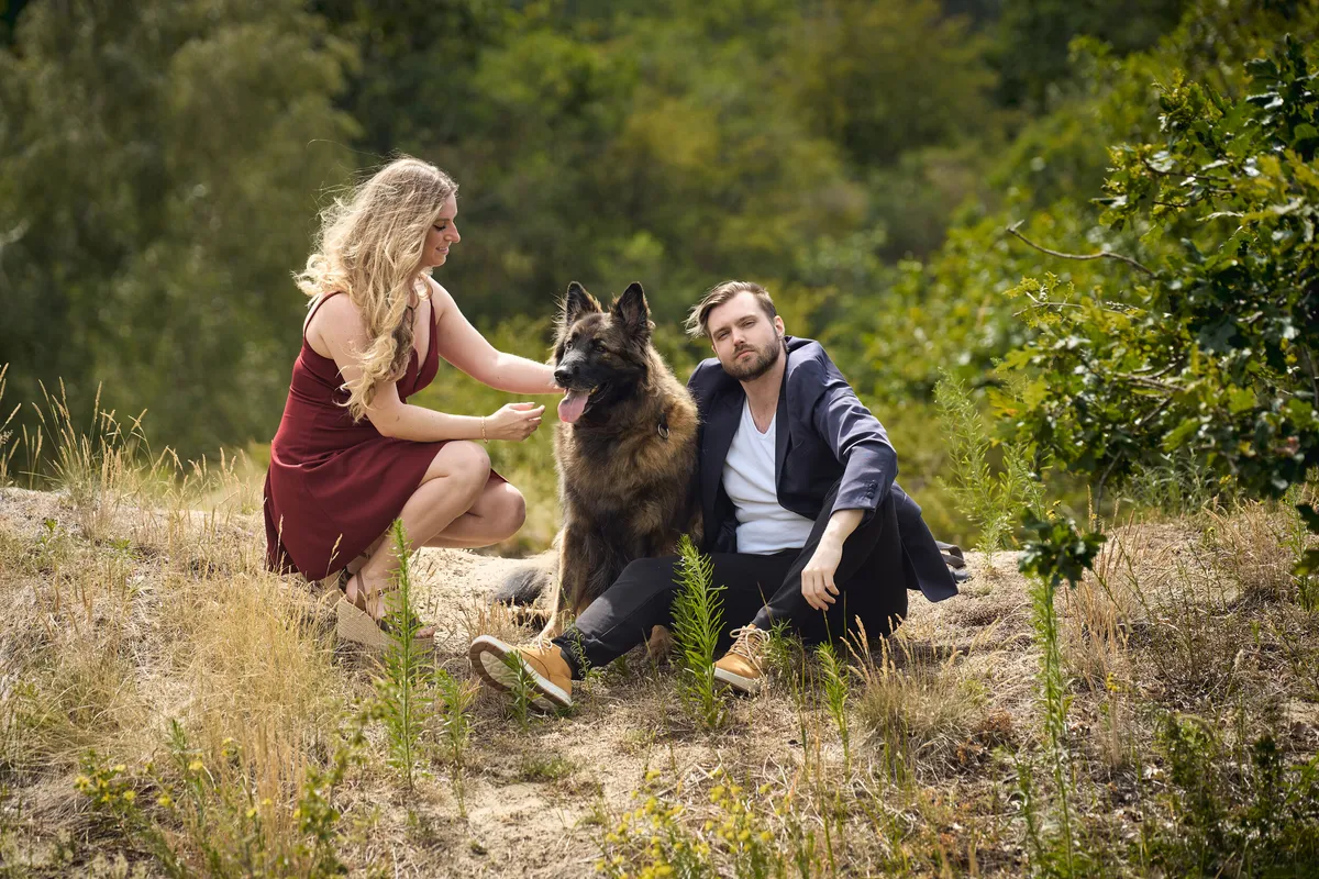 Dimitri en Kayleigh zitten met hun herdershond op een zandpad in de duinen