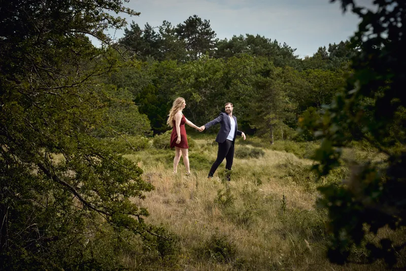 Dimitri en Kayleigh lopen hand in hand door een duinvallei met bomen