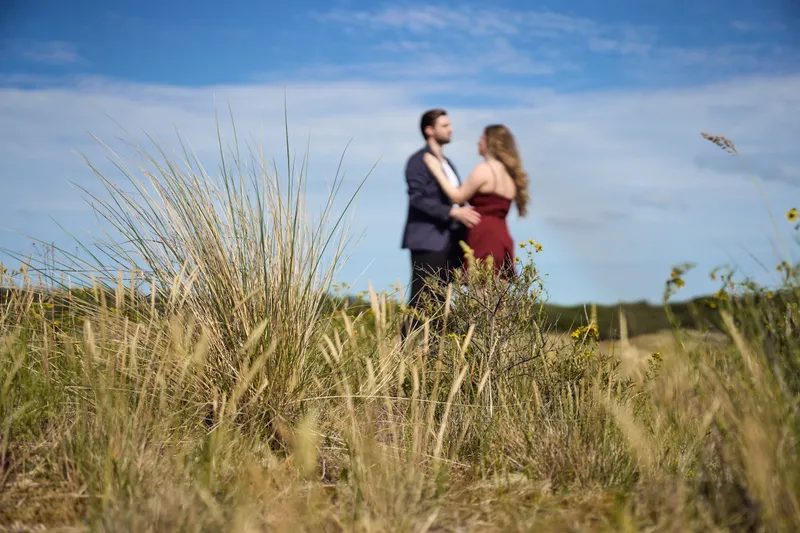 Dimitri en Kayleigh omhelzen elkaar in het helmgras tegen een blauwe lucht