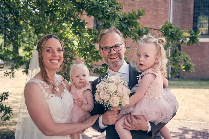 Mike en Ilja houden elk een van hun dochtertjes vast op het terrein van het hotel