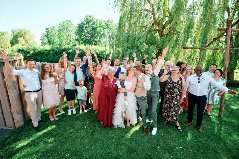 De hele groep in de tuin met de armen in de lucht