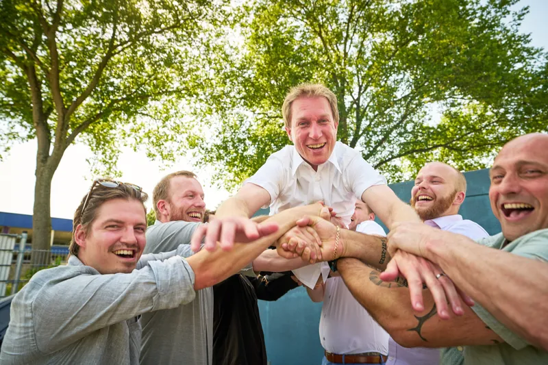 De mannen leggen lachend hun handen op elkaar