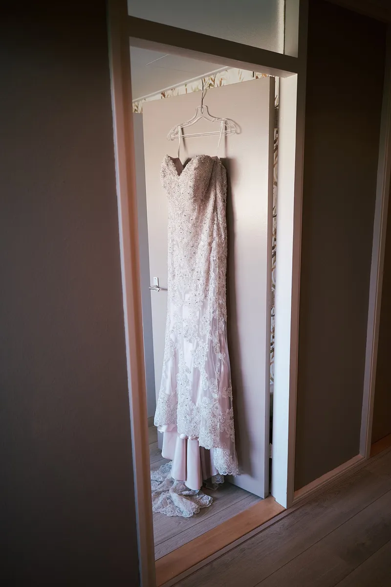De trouwjurk hangt in de deuropening