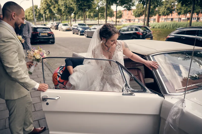 Robin helpt Wendy en haar jurk in de witte Ford Mustang