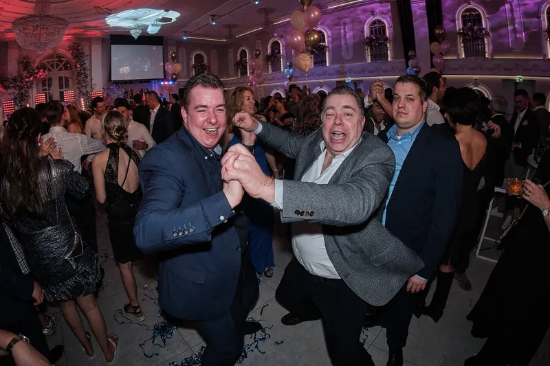 Twee gasten dansen arm in arm