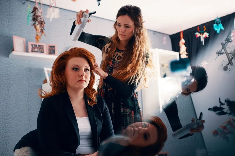 Naomi zit in de stoel terwijl haar haar wordt gedaan