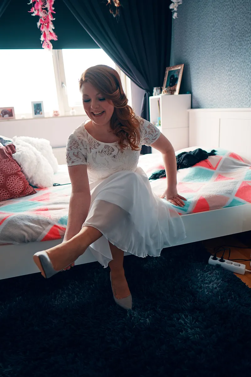 Naomi zit op het bed en trekt haar schoenen aan