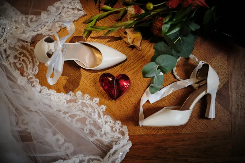 De witte schoenen van Natascha op de sleep van de jurk, met bloemen en een rood hartje