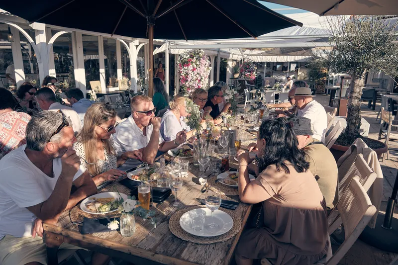 Lange tafels met gasten op het terras van Naturel